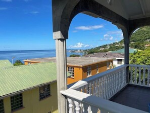 A balcony with a view of the sea and buildings. - Kingdom Rentals - AirBnCar (Loubiere)