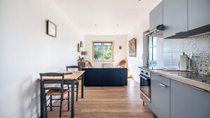 Een moderne keuken met een eethoek, houten vloeren en een groot raam.