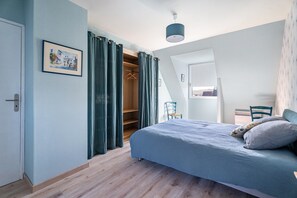 Een slaapkamer met een bed, een kledingkast en een stoel.