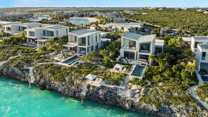 A coastal resort with modern villas, a pool, and a rocky shoreline. - Revitalize w/ Peaceful Balcony Views in Contemporary Island Paradise Room (Long Bay Hills)