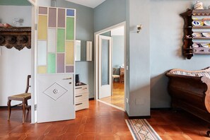 A room with a wooden chair, a cabinet with dishes, a tiled floor, and a door leading to another room.