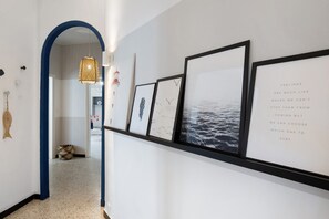 Un corridoio con opere d'arte incorniciate, un lampadario e un arco blu.