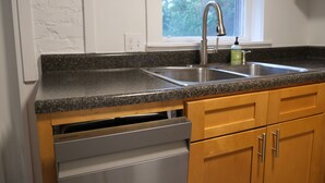 A kitchen with granite countertops, stainless steel sink, wooden cabinets, and a dishwasher. - Charming Getaway! Heart of Asheville Suite (Asheville)