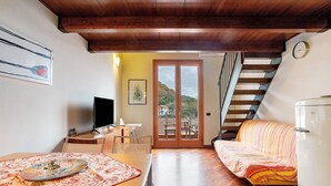 Una habitación con una mesa de madera, un sofá, un televisor y una puerta que da a un espacio exterior.