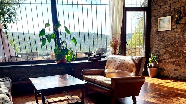 Ein Zimmer mit Holzboden, einer Couch, einem Couchtisch und Blick durch große Fenster.