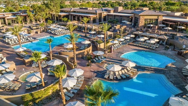 Ein Resort mit mehreren Schwimmbecken, Liegestühlen und Sonnenschirmen.