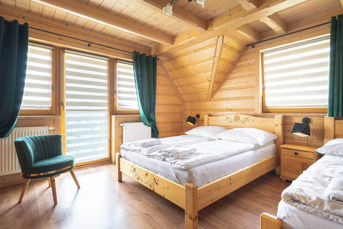 A wooden cabin bedroom with a bed, a chair, and a nightstand.