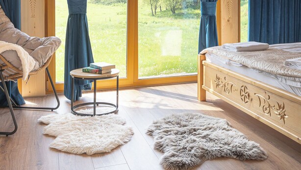 Une chambre avec une grande fenêtre, un lit, une chaise et une petite table.