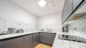 Eine moderne Küche mit Marmorarbeitsplatten, grauen Schränken und Holzboden.