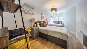 A modern bedroom with a bed, bedside tables, a desk, and a hanging light fixture. - Host Stay Apartment 5 Stanley Street (Liverpool)