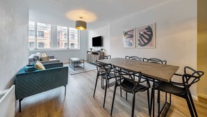 A modern living room with a dining table, chairs, a sofa, a TV, and artwork on the walls. - Host Stay Apartment 5 Stanley Street (Liverpool)
