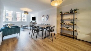 A modern living room with a dining area, wooden flooring, a sofa, a TV, and a bookshelf with plants. - Host Stay Apartment 5 Stanley Street (Liverpool)