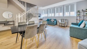 A modern living space with a dining area, a staircase, and a large window providing natural light. - Host Stay Apartment 8 Stanley Street (Liverpool)