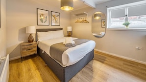 A modern bedroom with a bed, bedside tables, a mirror, and a window with a view. - Host Stay Apartment 8 Stanley Street (Liverpool)