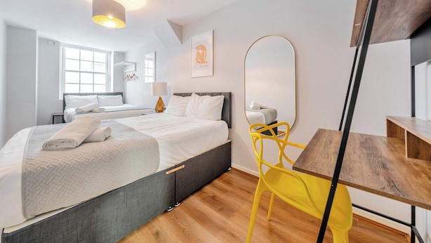 Un dormitorio moderno con una cama, una mesita de noche y un espejo.