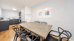 Una cocina moderna con encimera de mármol, una mesa de comedor de madera con seis sillas y dos cuadros en la pared.