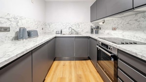 Una cocina moderna con encimeras de mármol, armarios grises y suelo de madera.