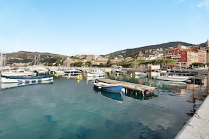 Un port de plaisance avec des bateaux amarrés, un quai et des bâtiments en arrière-plan.