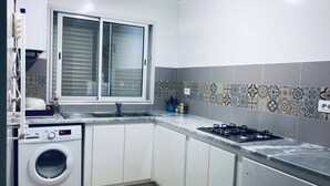 Eine moderne Küche mit Einbauwaschmaschine, Gasherd und Fenster mit Jalousien.