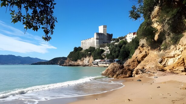 A beach with a large building on a cliff, calm water, and a clear sky. - Apartment '5 Terre - Lerici - La Caletta' with Sea View, Wi-Fi and Air Conditioning (Lerici)