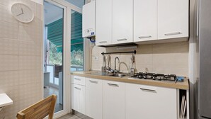 A kitchen with white cabinets, a gas stove, a sink, and a clock on the wall. - Apartment '5 Terre - Lerici - La Caletta' with Sea View, Wi-Fi and Air Conditioning (Lerici)