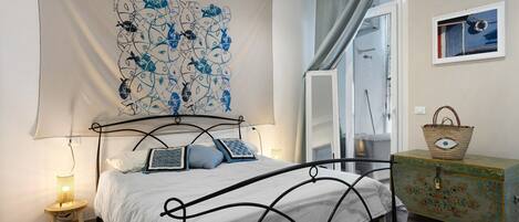 A bedroom with a bed, a wall tapestry, a dresser, and a window.