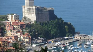 A coastal town with a prominent fortress-like structure, a marina with boats, and residential buildings with red roofs. - Apartment '5 Terre - Lerici - La Caletta' with Sea View, Wi-Fi and Air Conditioning (Lerici)