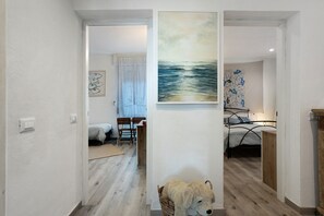 Ett rum med en säng, en tavla som hänger på väggen, en korg av rotting med en mjukdjursleksak i och ett trägolv.