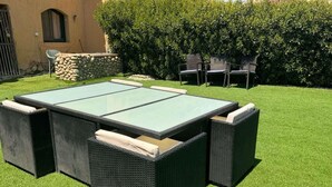 Un patio con tavolo in vetro e sedie in vimini.