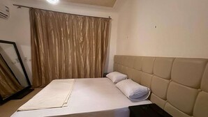 Una camera da letto con un letto, una testiera, un comodino e una tenda.