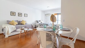 A modern living room with a sofa, a dining table set with plates and glasses, and a small side table. - Charming studio on Las Heras Avenue, Recoleta | 4P (Ciudad Autónoma de Buenos Aires)