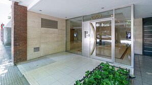 A modern building entrance with a glass door marked "2050", a tiled floor, and a brick column. - Charming studio on Las Heras Avenue, Recoleta | 4P (Ciudad Autónoma de Buenos Aires)