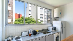 A modern kitchen with a built-in stove, microwave, sink, and washing machine. - Charming 2-Bedroom Apartment | Renovated | Cañitas (Ciudad Autónoma de Buenos Aires)