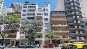 A multi-story residential building with balconies, a visible storefront, and parked cars. - Charming 2-Bedroom Apartment | Renovated | Cañitas (Ciudad Autónoma de Buenos Aires)