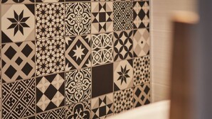 A bathroom with a tiled wall featuring various geometric and floral patterns. - AV Soterra a 2B in Vila (Ávila)