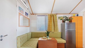 Una kitchenette compacta con refrigerador, una mesita con una planta y un sofá estampado de lunares.