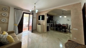 A spacious living area with a sofa, a TV, and a dining area with chairs and a table. - From Pupa SeaView Apartment (Vico Equense)