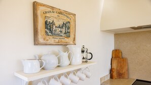 Een keuken met witte kasten, een houten aanrecht, een koffiezetapparaat en een vintage poster aan de muur.