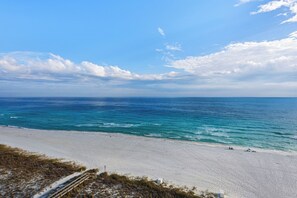 A beach with a wooden boardwalk leading to the shore, clear blue sky, and calm sea. - 🌊☮️A Peace of Paradise | Two Primary Suites | Luxury Navarre Towers 1104🌊 (Navarre)