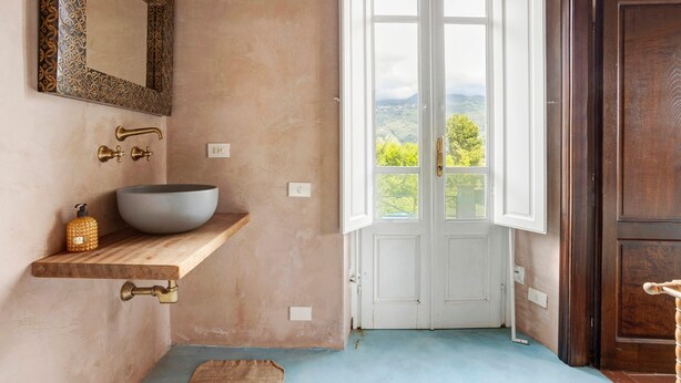 A bathroom with a large mirror, a vessel sink, a wooden shelf, and a view through an open door. - Room 'Camera Alex - Marinsky' with Shared Garden, Wi-Fi and Air Conditioning (Pietrasanta)