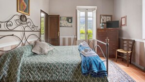 A bedroom with a bed, a chair, a dresser, and a television. - Room 'Camera Alex - Marinsky' with Shared Garden, Wi-Fi and Air Conditioning (Pietrasanta)