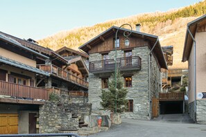 A traditional mountain lodge with stone walls, wooden balconies, and a clear view of the surrounding forest.