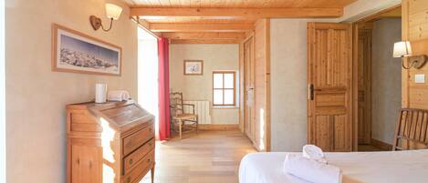 Ein Zimmer mit Holzwänden, einem Bett, einem Schminktisch und einem Stuhl.