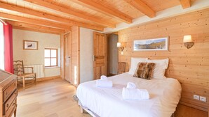 Un dormitorio con paneles de madera, una cama, un tocador, una silla y una ventana.