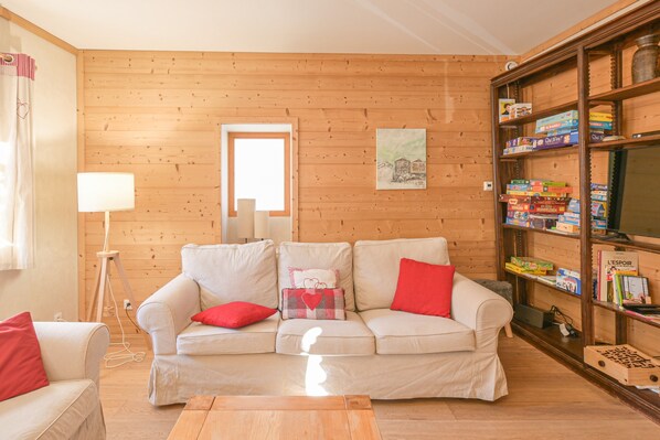 A cozy living room with a beige sofa, a wooden bookshelf, and a lamp.