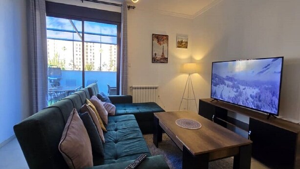 A modern living room with a sofa, a coffee table, a TV, and a floor lamp.