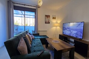 Ein modernes Wohnzimmer mit einer Couch, einem Couchtisch, einem Fernseher und einer Stehlampe.