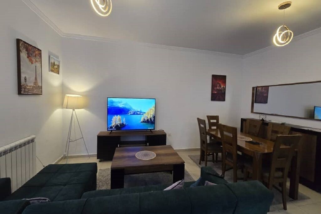 A living room with a TV, sofa, dining table, and chairs.