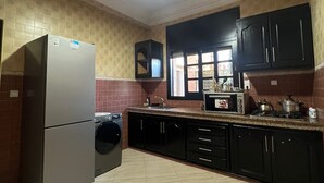 Une cuisine équipée d’un réfrigérateur, d’un lave-linge, d’un four à micro-ondes et d’une cuisinière.