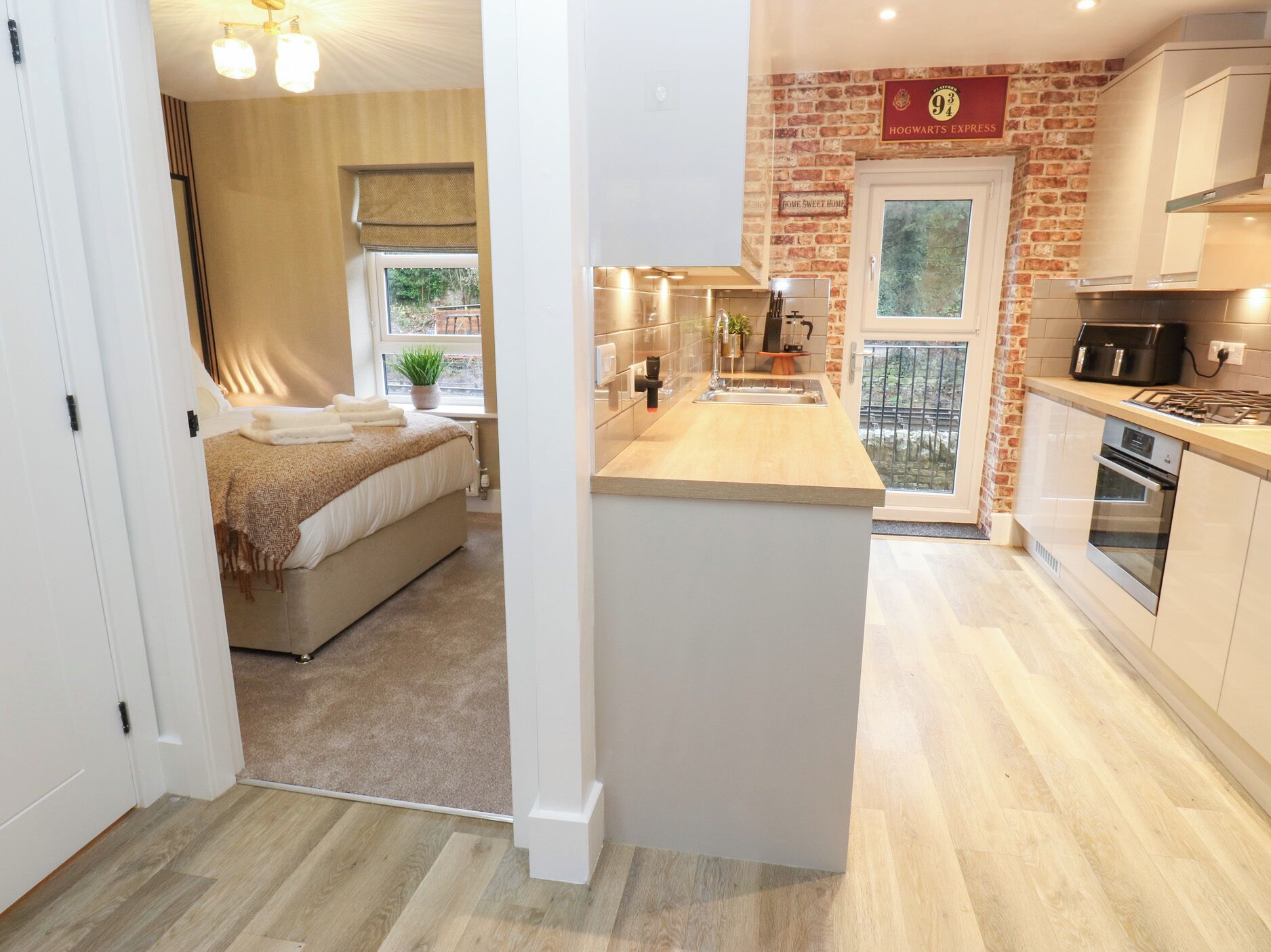 Una cocina moderna con una pared de ladrillo decorativa, una zona de comedor y un dormitorio con un ventanal grande.